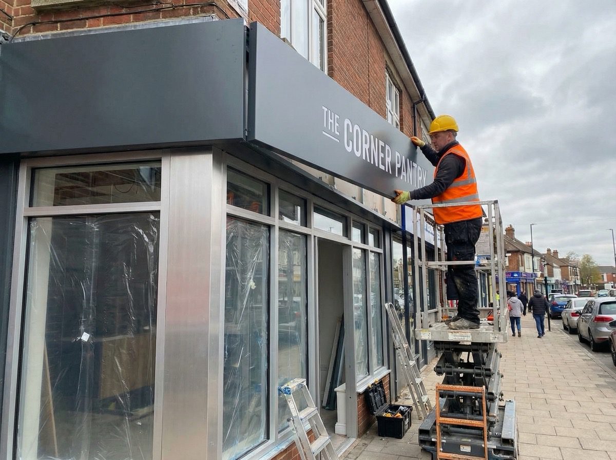 Worker installing fascia sign as part of shop front project